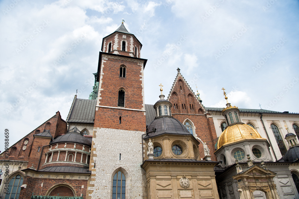 Old city architecture concept. Tower belfry with steeples in Krakow. Architectural heritage. Old or ancient church or cathedral with many window made out of red brick. Tower with cross on top of roof Old city architecture concept. Tower belfry with steeples in Krakow. Architectural heritage. Old or ancient church or cathedral with many window made out of red brick. Tower with cross on top of roof