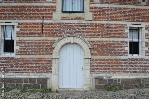 Closeup photograph of windows and a white arched door in a historical brick-and-limestone building at Park Abbey, Leuven, Belgium.