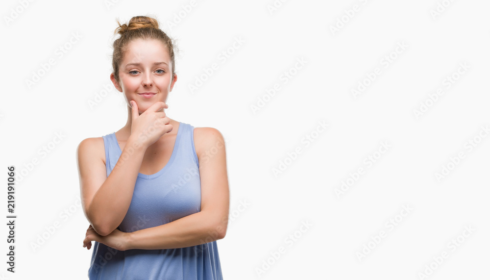 Young blonde woman looking confident at the camera with smile with crossed arms and hand raised on chin. Thinking positive. Young blonde woman looking confident at the camera with smile with crossed arms and hand raised on chin. Thinking positive.