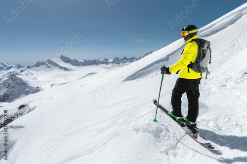 Portrait of a professional freerider skier standing on a snowy slope against the background of snow-capped mountains. The concept of winter sports