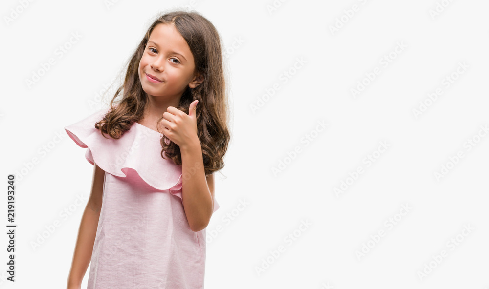 Brunette hispanic girl wearing pink dress doing happy thumbs up gesture with hand. Approving expression looking at the camera with showing success. Brunette hispanic girl wearing pink dress doing happy thumbs up gesture with hand. Approving expression looking at the camera with showing success.