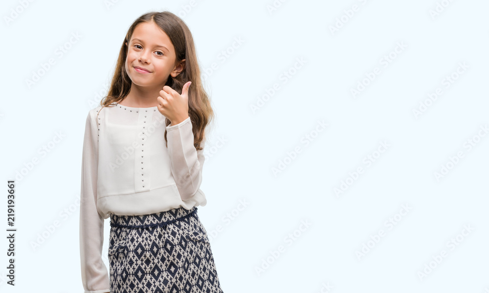 Brunette hispanic girl doing happy thumbs up gesture with hand. Approving expression looking at the camera with showing success. Brunette hispanic girl doing happy thumbs up gesture with hand. Approving expression looking at the camera with showing success.