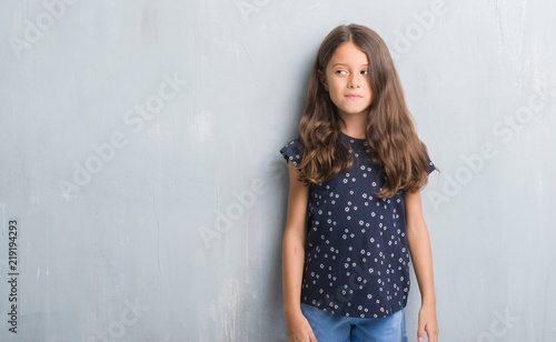 Fotografija Young hispanic kid over grunge grey wall smiling looking side and staring away thinking