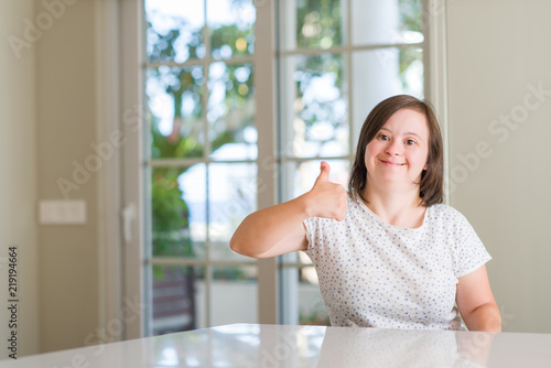Down syndrome woman at home happy with big smile doing ok sign  thumb up with fingers  excellent sign