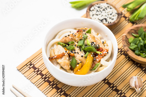 Udon stir-fry noodles with chicken and vegetables on white.