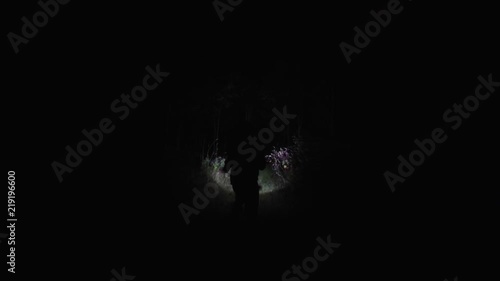 Chasing girl through the woods at night. Stalker or killer runs after terrified woman in dark forest. Moving through scary wooded area lit only with flashlight after victim. photo