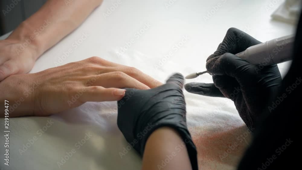 Closeup shot of a beautician applying nail polish to female nail in a nail salon. Woman getting nail manicure, spa treatments. Closeup shot of a beautician applying nail polish to female nail in a nail salon. Woman getting nail manicure, spa treatments.