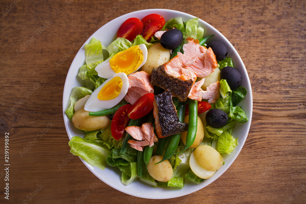 Salad Nicoise with salmon. Tomato, green beans, new potato, olives and lettuce salad with salmon. overhead, horizontal