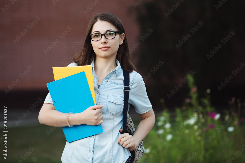 Student outdoor portrait. Caucasian female college or university girl holding folders. Student outdoor portrait. Caucasian female college or university girl holding folders.