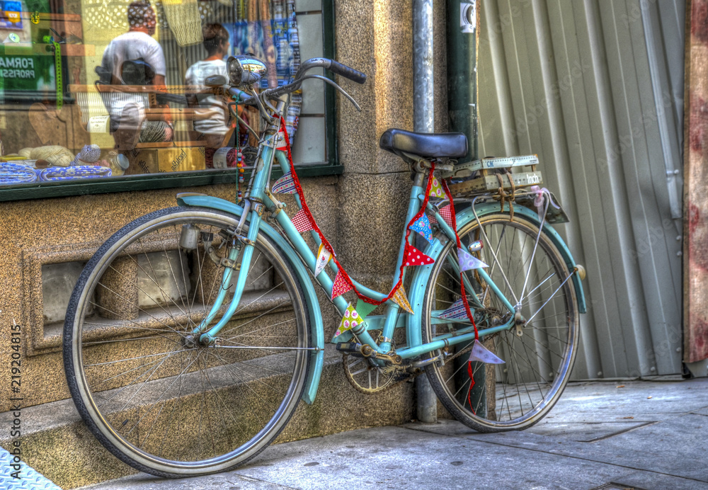Old colourful bicycle by a street in Porto, in front of a shop 