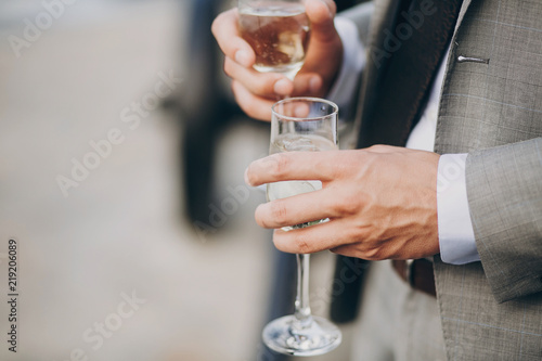 hands of stylish people cheering with glasses of champagne, luxury wedding reception, rich celebration. guests toasting at christmas luxury celebration feast