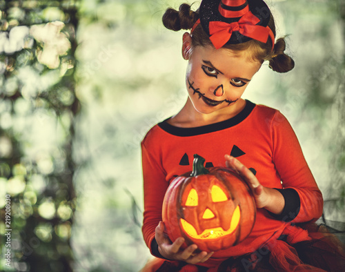 Happy Halloween! horrible creepy child girl in  pumpkin costume  in forest.