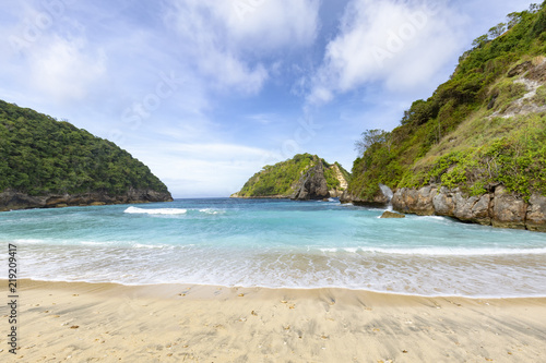 A wide angle view of the surf slowly breaking on Atuh Beach in Nusa Penida in Indonesia.