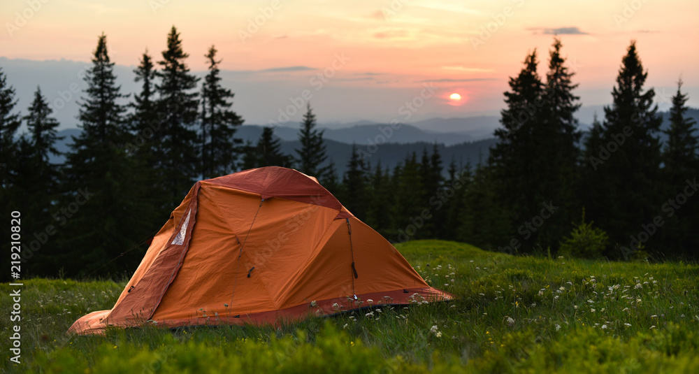Panorama of camping in mountain. Tent on valley in the sunset overlooking mountains and a forest