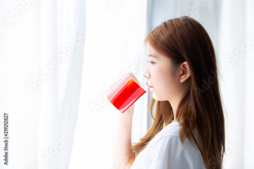 Beautiful of portrait young asian woman with drink acup of coffee standing curtain window background in bedroom, girl relax in morning at home, lifestyle concept. photo