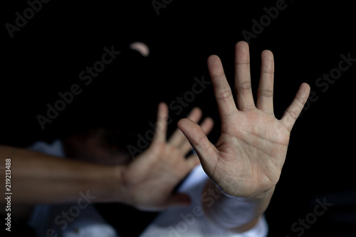 The palm of a female hand giving the signal to stop. The dark, moody image is a concept of a woman being abused, raped, beaten, threatened, robbed, domestic violence etc.