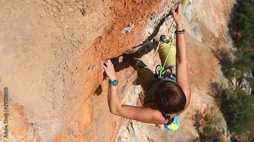 young woman rock climber climbing on the cliff. female climber climbing very hard route making hard moves and falling