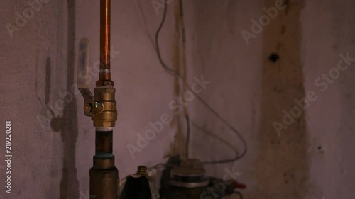 The main water shut off valve in an unfinished basement - plumbing concept photo