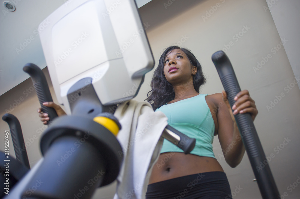 gym portrait of young attractive black african American woman training elliptical machine workout at fitness club working hard gym portrait of young attractive black african American woman training elliptical machine workout at fitness club working hard