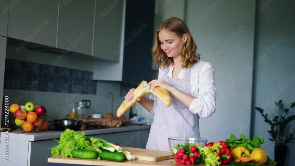 Happy girl breaking and eating french baguette in kitchen. Woman tasty baked baguette bread. Natural ingredients for healthy dieting. Smiling girl eat healthy food. Healthy cooking Happy girl breaking and eating french baguette in kitchen. Woman tasty baked baguette bread. Natural ingredients for healthy dieting. Smiling girl eat healthy food. Healthy cooking