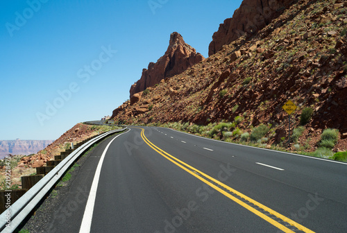Lonely, Winding Asphalt Road in Arizona, USA with Two Yellow Center Lines and Rocky Orange Hillside © Dietmar
