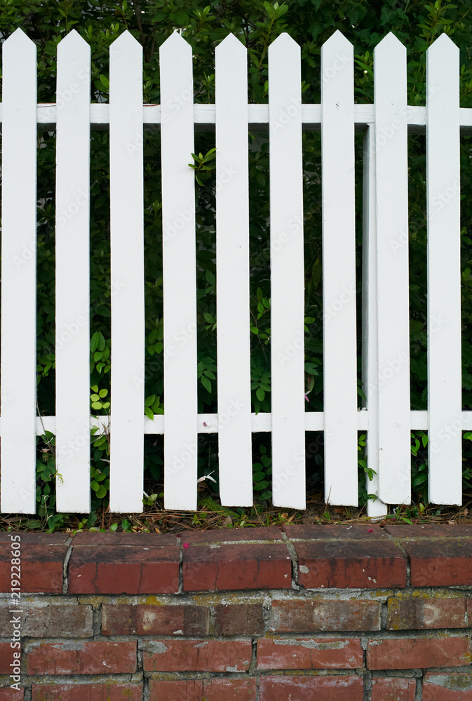 Wooden Picket Fence Painted White on a Base of Red Bricks Wooden Picket Fence Painted White on a Base of Red Bricks