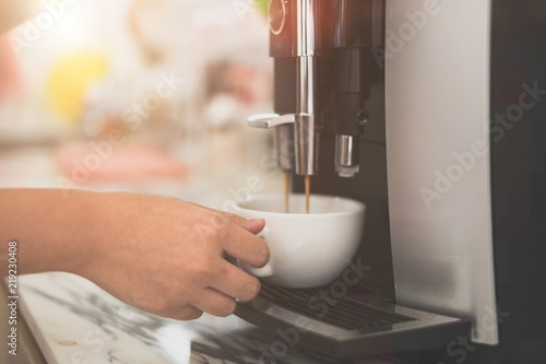 Woman making fresh espresso in coffee maker. coffee machine makes coffee. Barista Coffee Maker Machine Grinder Portafilter Concept photo