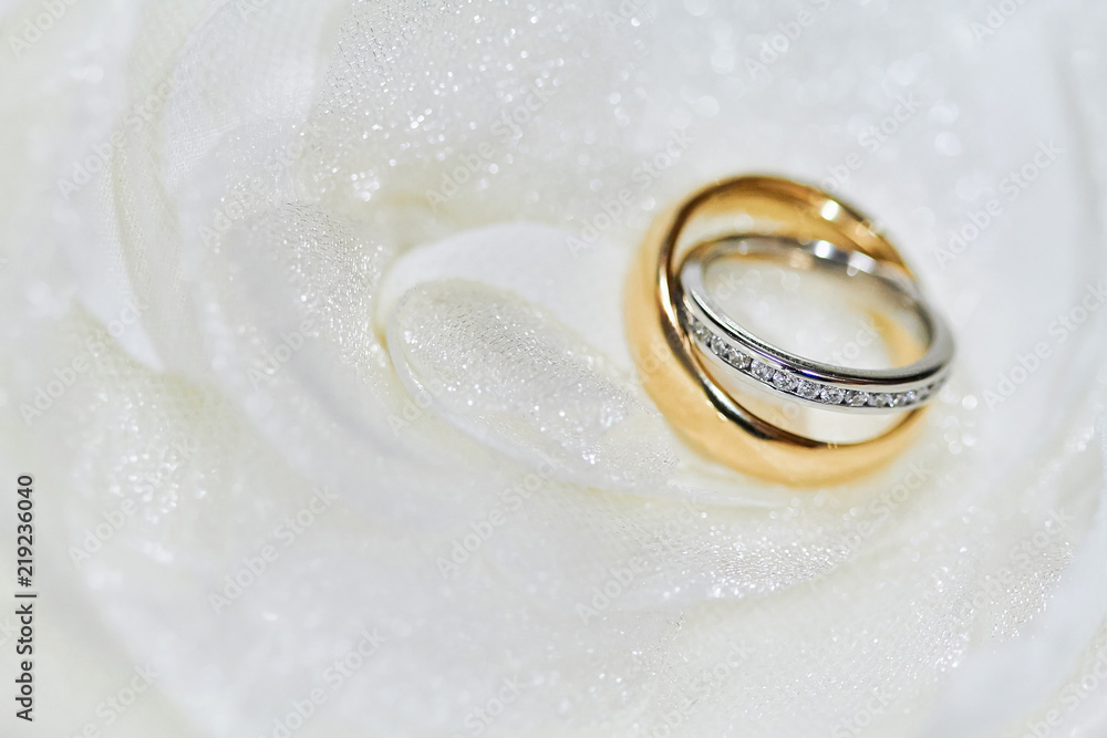 Selective focus on the diamond head of couple rings with shallow deph of field on the white fabric Selective focus on the diamond head of couple rings with shallow deph of field on the white fabric