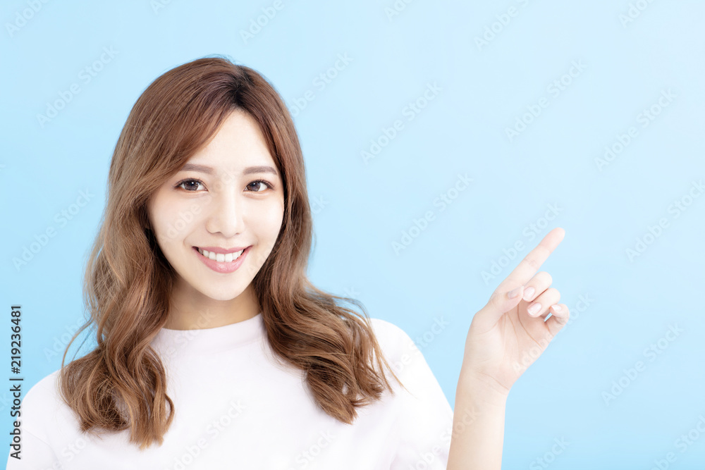 smiling Young woman pointing at blue background smiling Young woman pointing at blue background