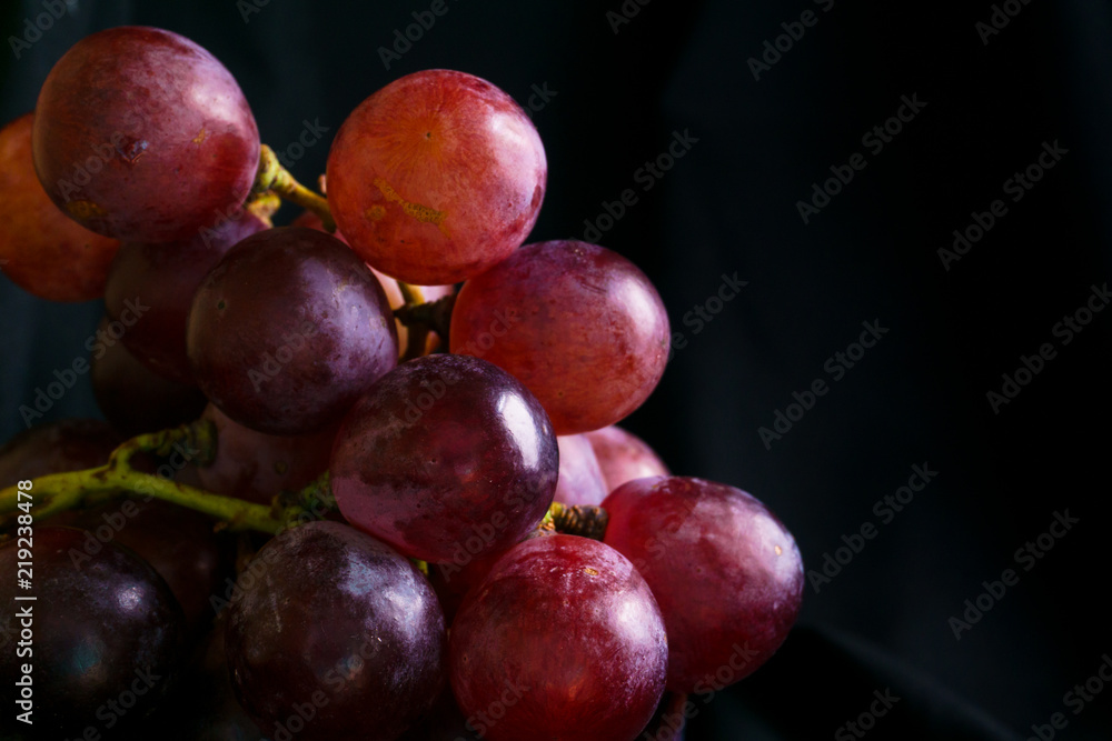 closu up red grapes in a white bowl in the dark corner closu up red grapes in a white bowl in the dark corner