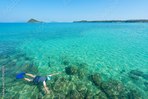 Tourists snorkel in crystal turquoise water near tropical resort in Phuket, Thailand. Summer, Vacation, Travel and Holiday concept.
