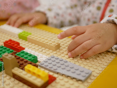 Hands of a baby playing colorful interlocking plastic bricks - child development through playing toys