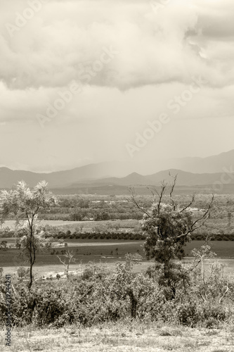 Rain over hills with trees and farms on the Atherton Tableland in Queensland, Australia, sepia toned photo