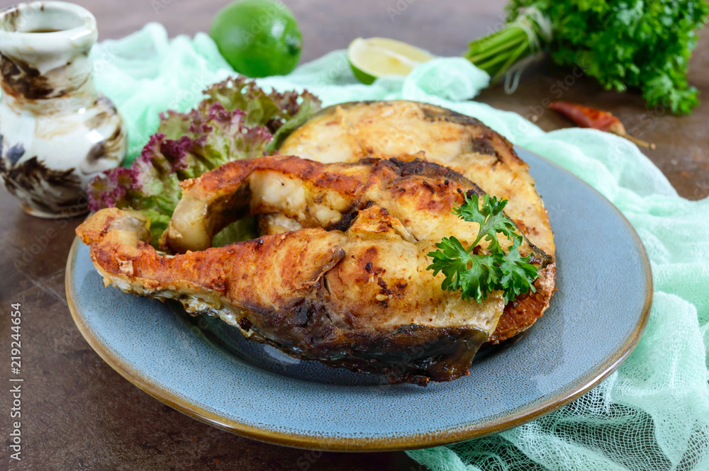 Large steaks of grilled fish with lettuce on a plate. Large steaks of grilled fish with lettuce on a plate.