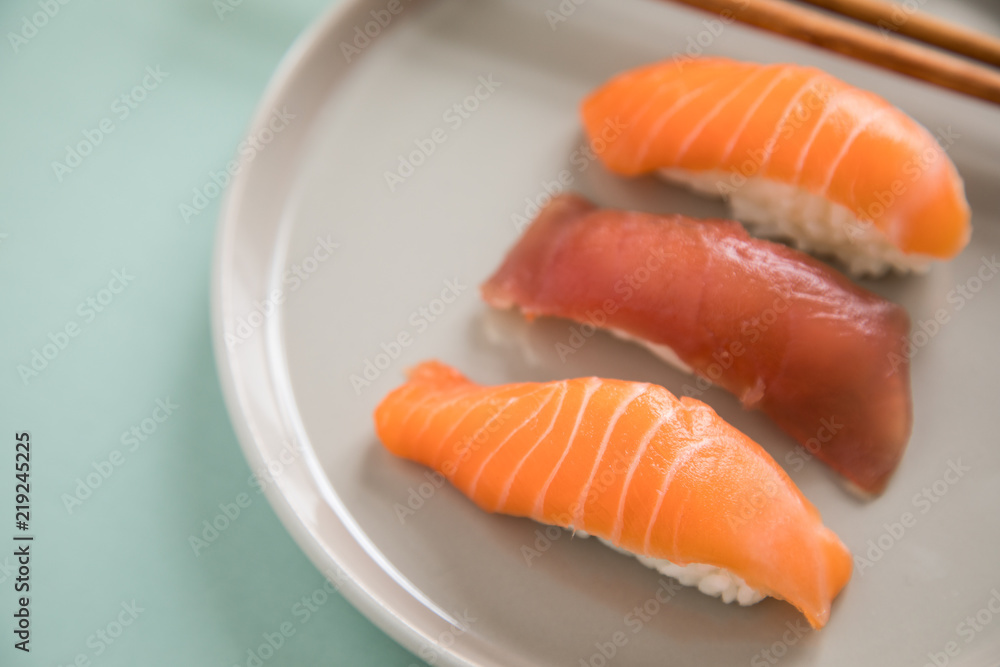 Lachs und Tunfisch Nigiri Sushi mit Holz Stäbchen auf Porzellan Teller Lachs und Tunfisch Nigiri Sushi mit Holz Stäbchen auf Porzellan Teller