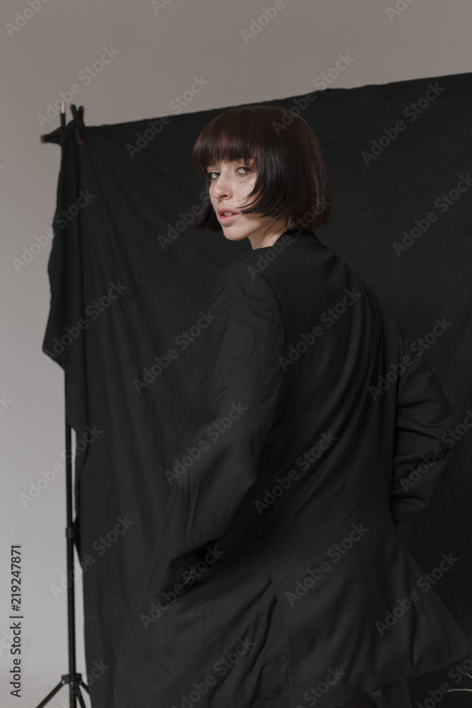 Beautiful, stylish girl in fashionable black clothes with short black hair. Fashionable studio shot