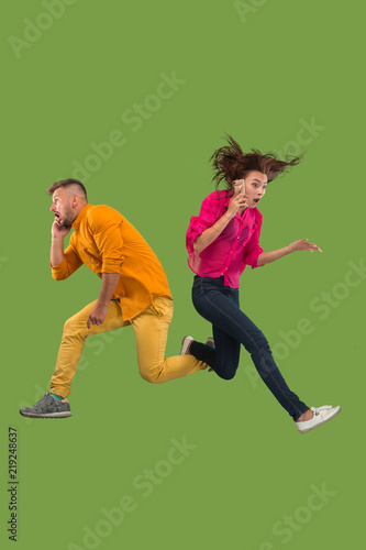 Full length of young couple with mobile phone while jumping