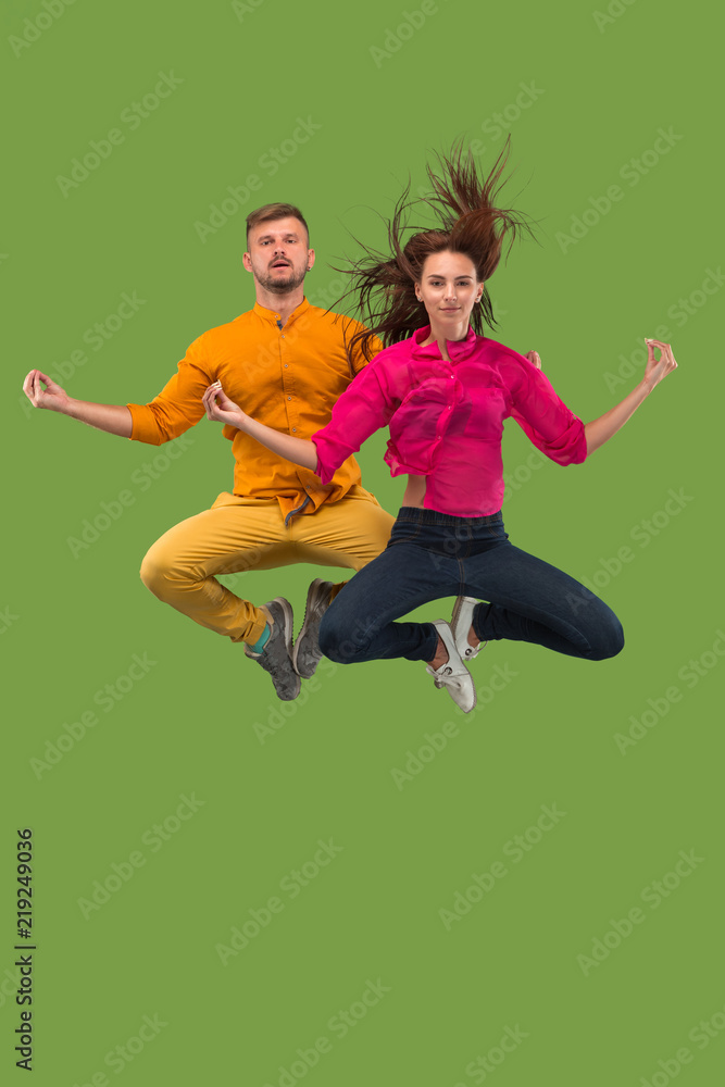 Freedom in moving. Pretty young couple jumping against green background