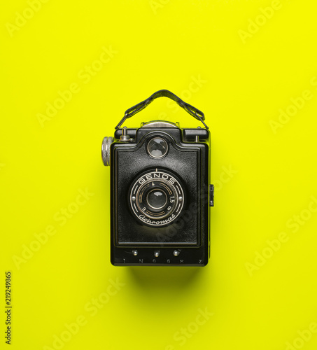 Fototapeta black old camera genos on green yellow background isolated from above