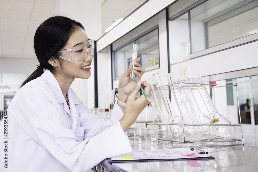 Interior of clean modern white medical or chemical laboratory background.Laboratory scientist working at lab with test tubes and report. Laboratory concept with Asian woman chemist. Interior of clean modern white medical or chemical laboratory background.Laboratory scientist working at lab with test tubes and report. Laboratory concept with Asian woman chemist.