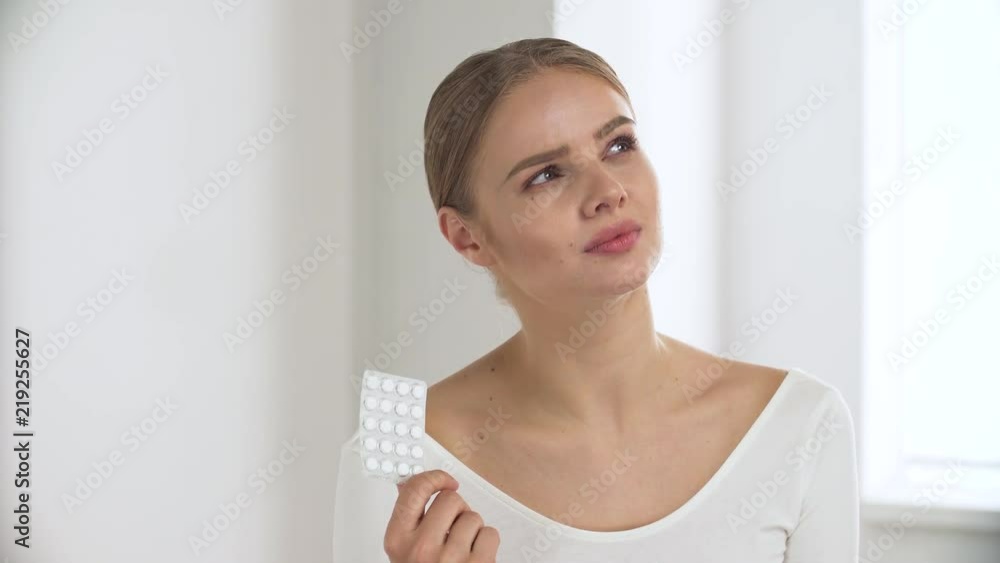Medicine. Thoughtful Woman With Pills In Hand At White Interior Medicine. Thoughtful Woman With Pills In Hand At White Interior