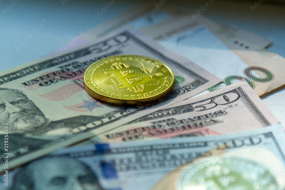 Yellow coin bitcoin against the background of dollar bills. One coin is bitcoin and dollars. A beautiful blurred photo of the crypto currency and the US currency.