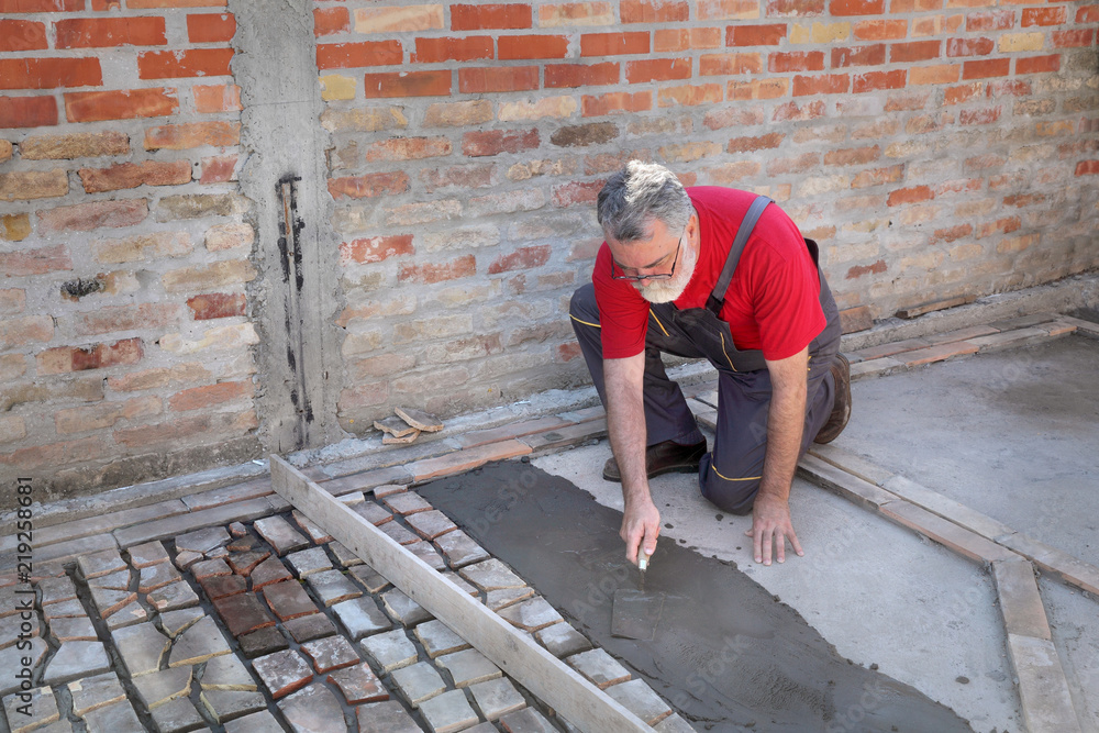 Old tiles recycling, making terrace or pavement using tile pieces, worker spreading mortar or tile adhesive using trowel Old tiles recycling, making terrace or pavement using tile pieces, worker spreading mortar or tile adhesive using trowel