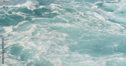 Frothy blue foam along shoreline during big wave session