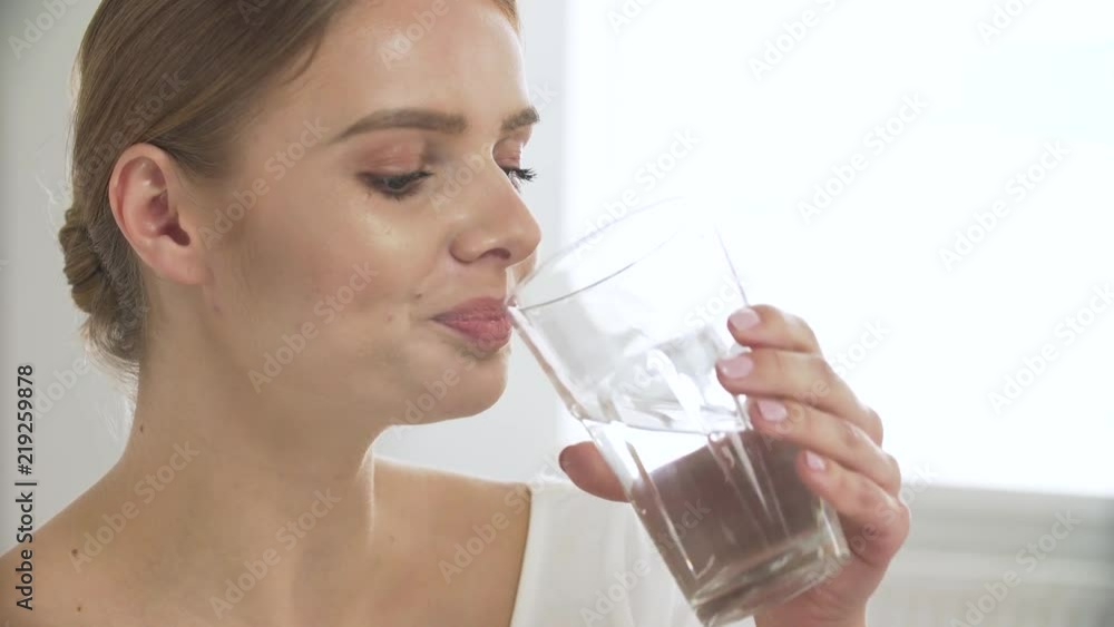Woman Drinking Water From Glass And Looking At Camera Woman Drinking Water From Glass And Looking At Camera