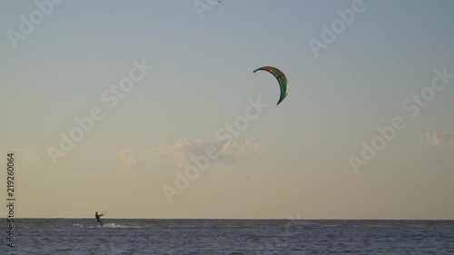 A man in the windy afternoon engage kitesurfing at sea, birds fly across the sky photo