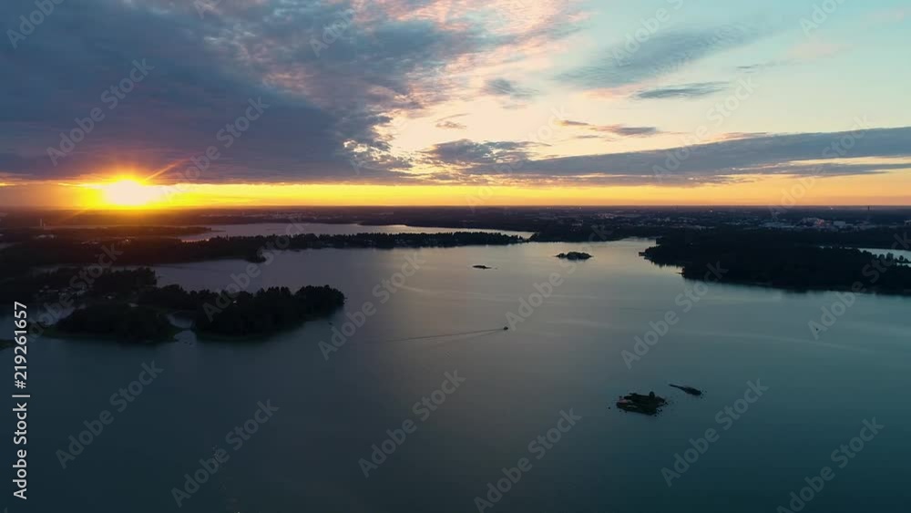 Beautiful 4K sunset. Sun shining behind and bellow clouds low from horizon and boat traveling. Drone flying and turning around slowly. Lauttasaari, Mustasaari, Hevossaari, Helsinki capital of Finland. Beautiful 4K sunset. Sun shining behind and bellow clouds low from horizon and boat traveling. Drone flying and turning around slowly. Lauttasaari, Mustasaari, Hevossaari, Helsinki capital of Finland.