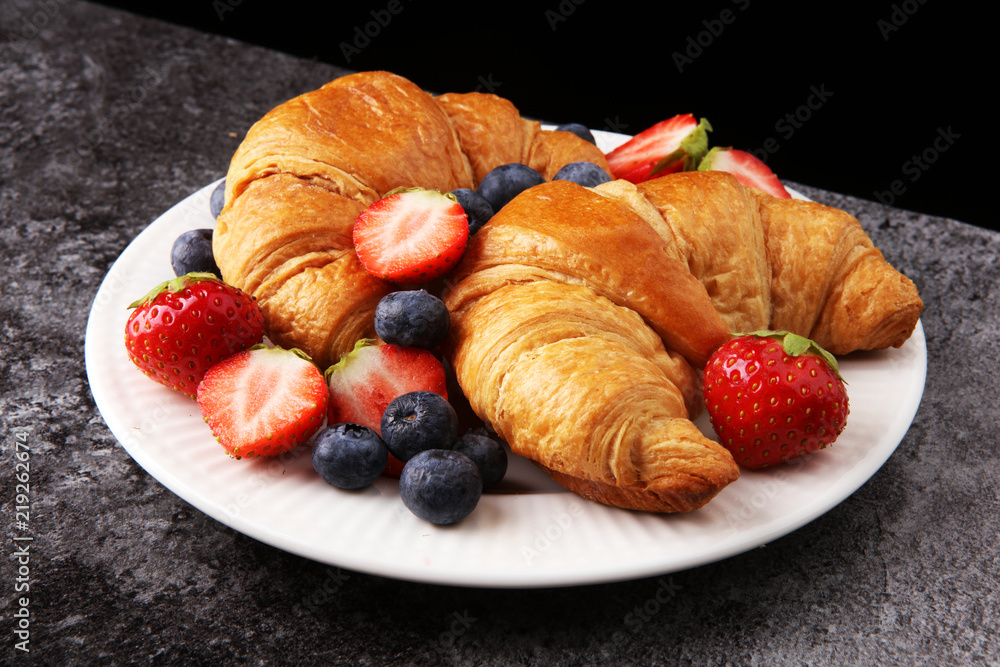 Delicious breakfast with fresh croissants and ripe berries on old marble background Delicious breakfast with fresh croissants and ripe berries on old marble background