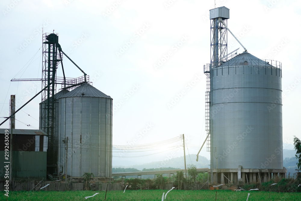 View of rice and corn factory with huge metal seed storages place between rice field View of rice and corn factory with huge metal seed storages place between rice field