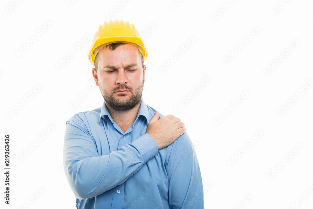 Young architect with yellow helmet showing shoulder pain gesture Young architect with yellow helmet showing shoulder pain gesture
